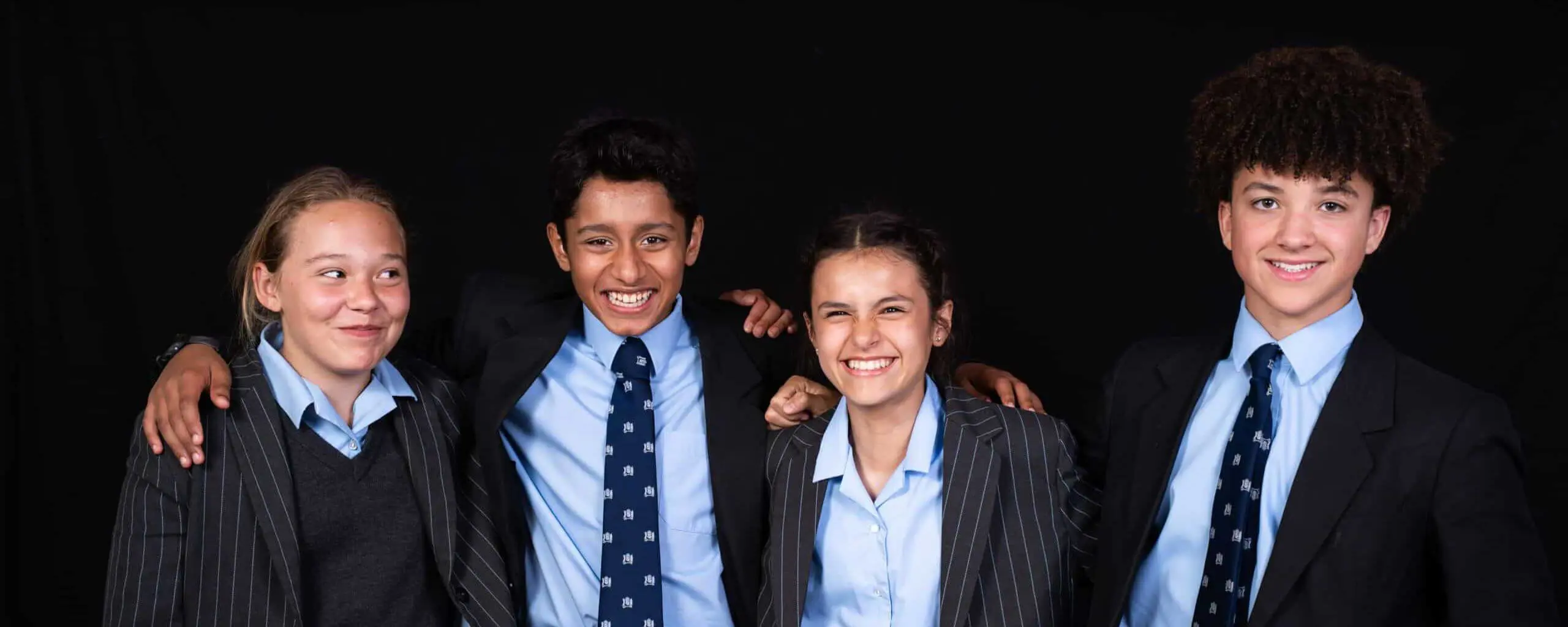 Ipswich School Year 7 pupils smiling for a photograph with their arms around each others' shoulders.