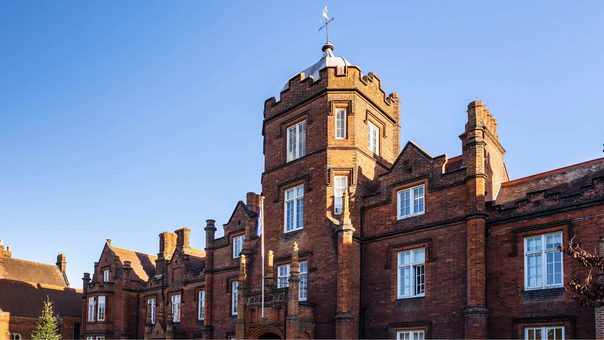 Fresh, vibrant image of the main school building, surrounded by lush greenery and bathed in natural colour.