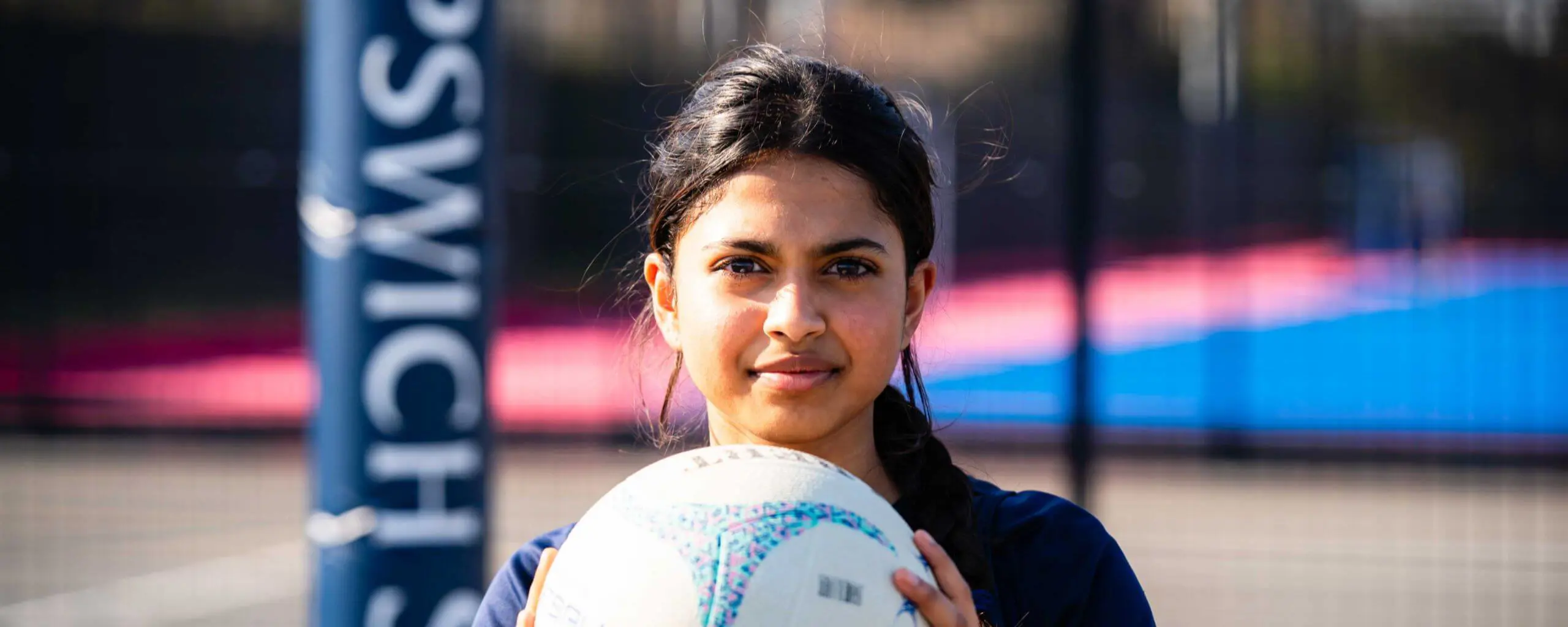 Ipswich School senior student holding a netball on a netball court.