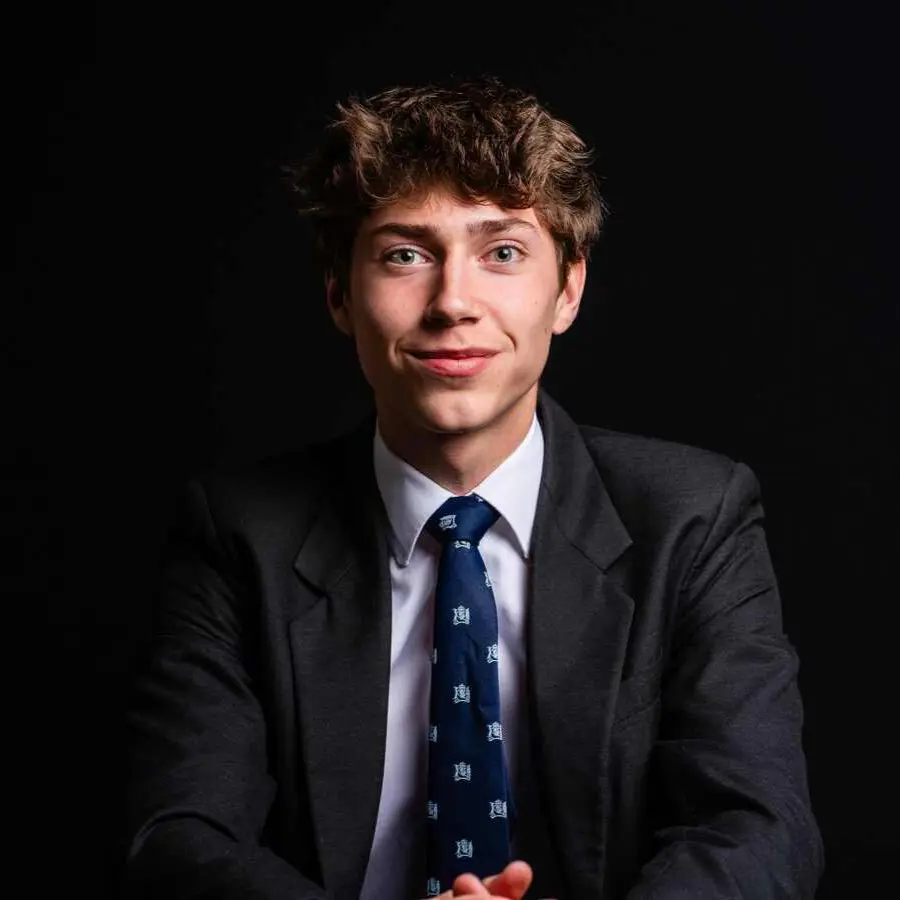 Senior boy, smartly dressed in uniform, looking directly at the camera with a confident smile.